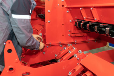Technician tightening bolted joint during agricultural machine assembly, ensuring structural integrity.