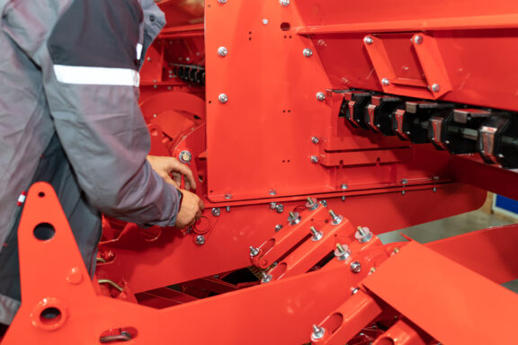 Technician tightening bolted joint during agricultural machine assembly, ensuring structural integrity.